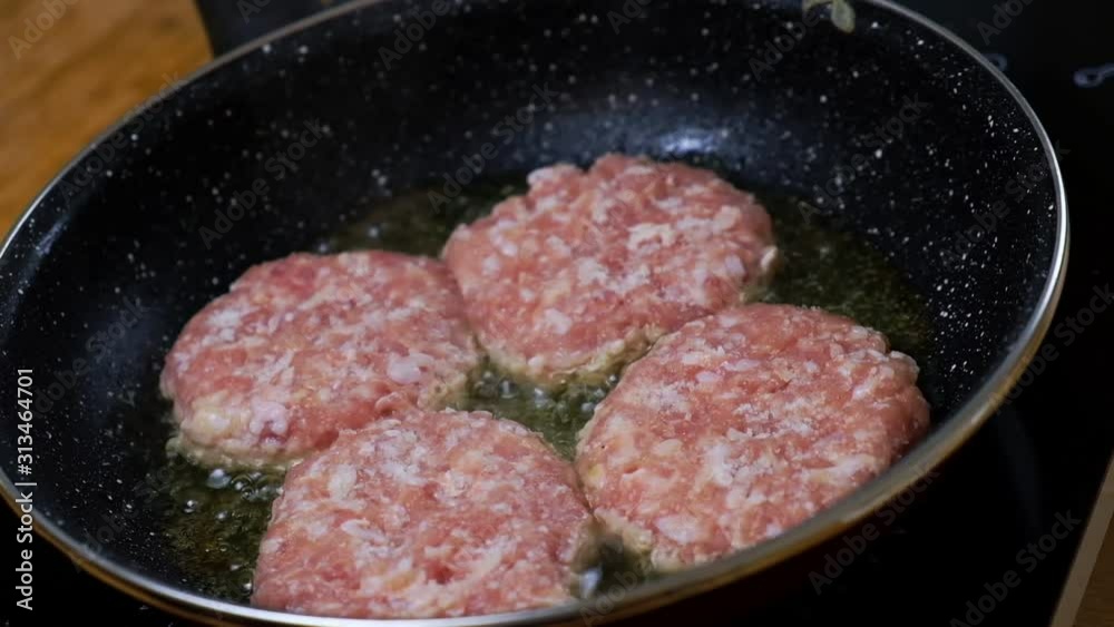 Frying a burger in a pan. Close-up of cooking fast food. Grilled. Frying a burger in a pan. Close-up of cooking fast food. Grilled.