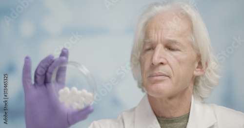 Senior scientist looking at sample of pills