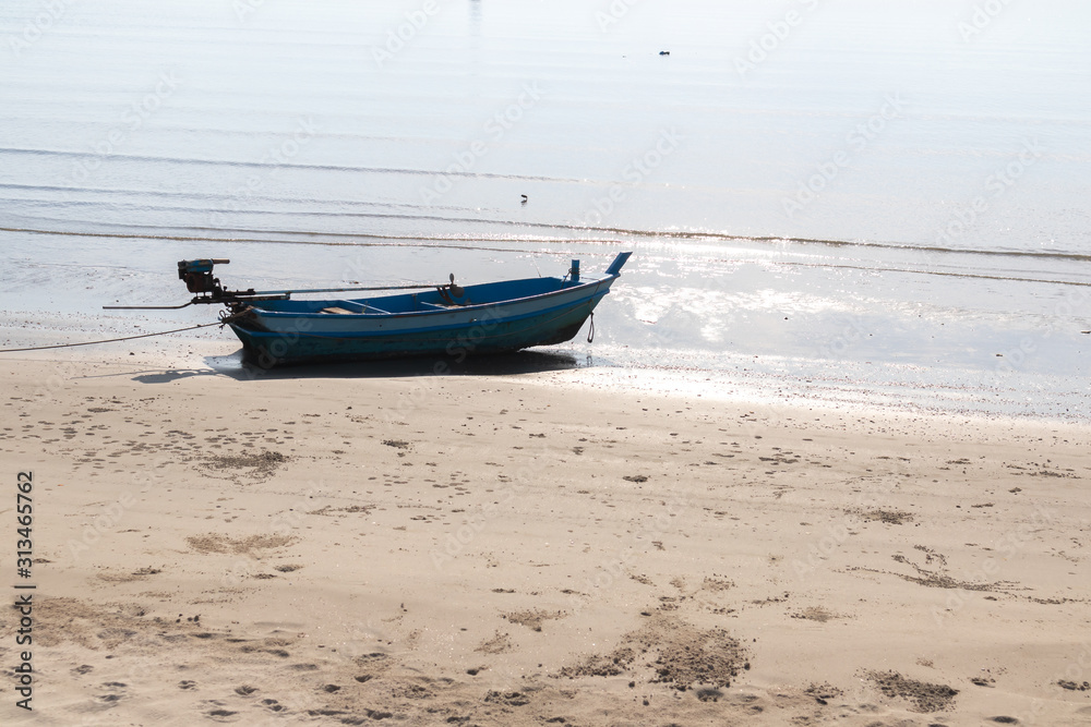 Naklejka premium Small fishing boats aground on the beach with trees in the background.
