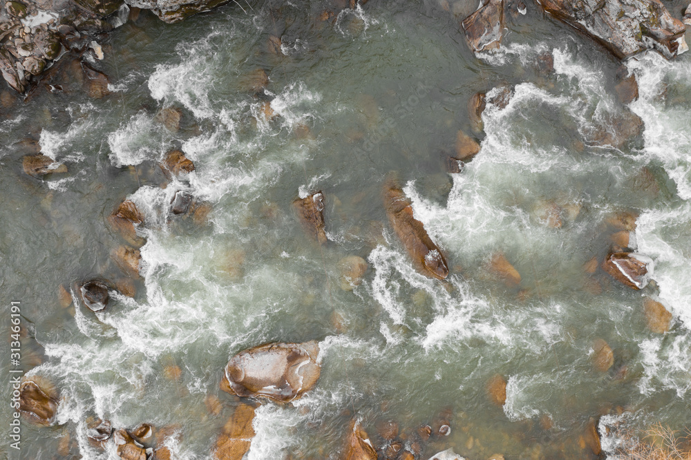 Top-down drone view of rapids of mountain river with wet boulders and pebble shore. Beautiful and powerful azure river stream with large stones. Nature concept