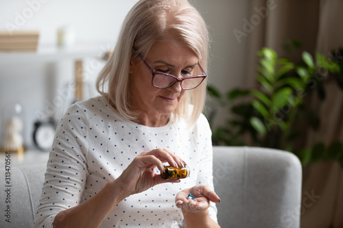 Elderly female pensioner having daily medicines at home photo