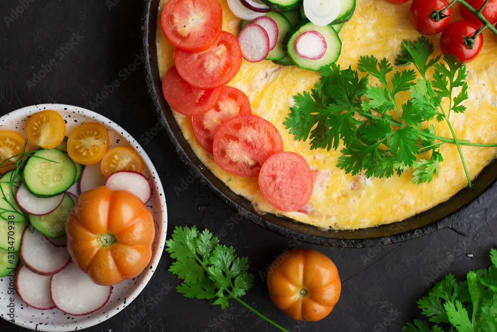 One pan dish. Homemade farm egg omelet with fresh, seasonal, natural vegetables and herbs. Tomatoes, cucumbers, radishes, parsley, organic egg. Healthy, simple nutrition. Top view