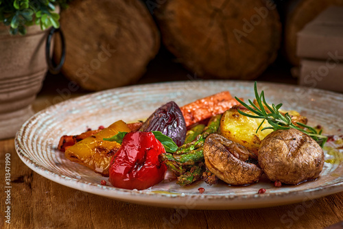 Grilled green vegetables - bell pepper, onion, potatoes, markov and rosemary on a plate. On a wooden table close-up photo