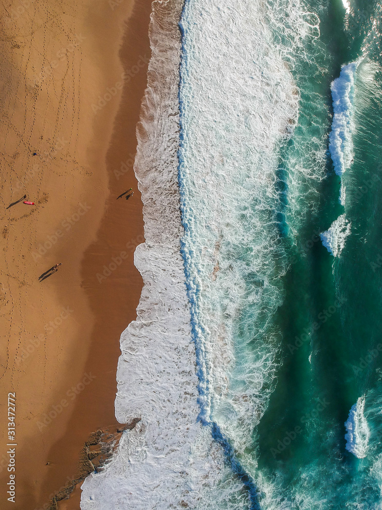 Sand beach aerial, top view of a beautiful sandy beach aerial shot with the blue waves rolling into the shore Sand beach aerial, top view of a beautiful sandy beach aerial shot with the blue waves rolling into the shore