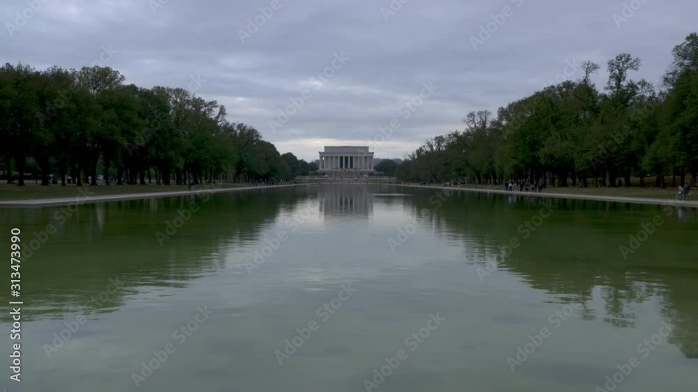 Superwide Beautiful shot of Lincoln memorial shot above shimmering reflecting pool as crowds move about memorial at sunset Superwide Beautiful shot of Lincoln memorial shot above shimmering reflecting pool as crowds move about memorial at sunset