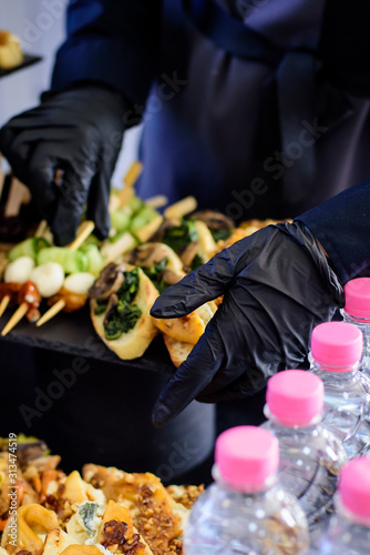 Hands in black gloves serves sandwiches. Catering