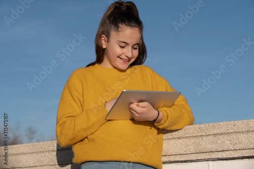 happy girl with a ipad in a park  with a yellow sweater