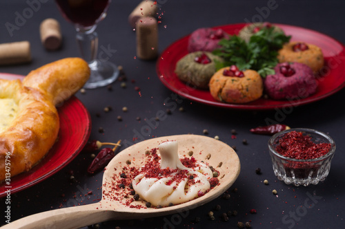 Georgian food on black table. khinkali, phali, khachapuri with tomatos, adjika and a glass of wine.