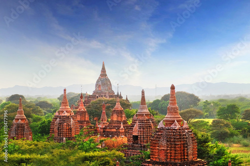 Blue sky above temples surrounded by green vegetation in old Bagan, Myanmar.