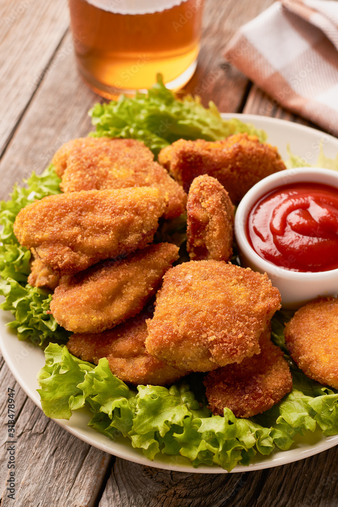 Close up of chicken nuggets with ketchup and lettuce on a wooden background Close up of chicken nuggets with ketchup and lettuce on a wooden background