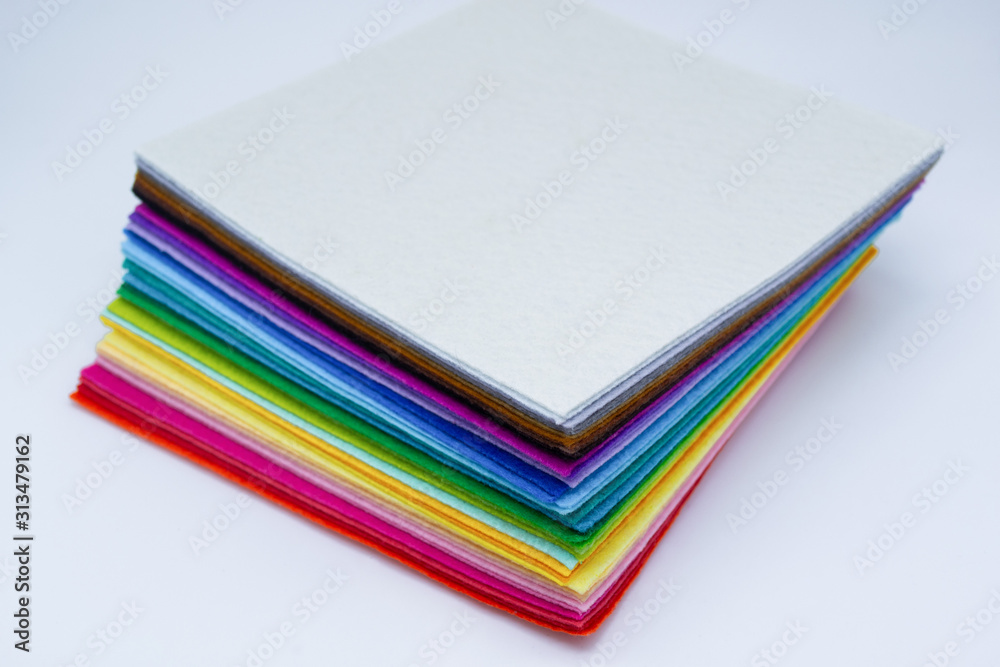 A stack of felt pieces arranged in perfect rainbow colors from white, black, brown, purple, blue, green, yellow, orange and red. Isolated. Copy space
