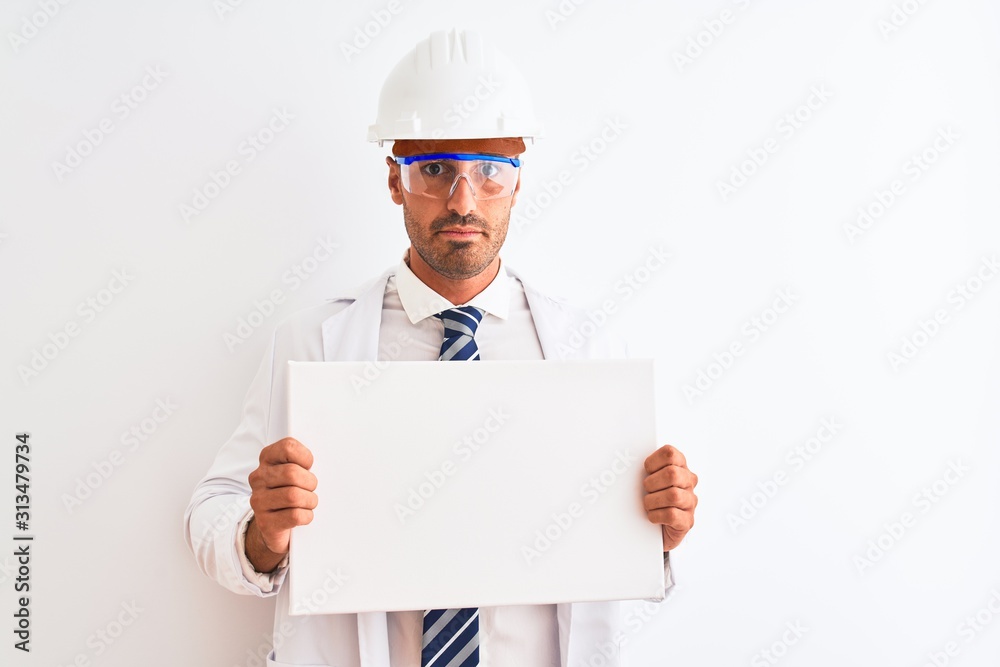 Young chemist man wearing security helmet holding signboard over isolated background with a confident expression on smart face thinking serious Young chemist man wearing security helmet holding signboard over isolated background with a confident expression on smart face thinking serious