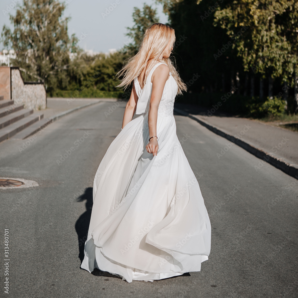 young adult blonde in a white dress is spinning, feeling freedom young adult blonde in a white dress is spinning, feeling freedom