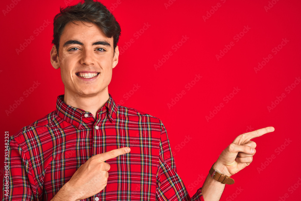 Teenager boy wearing red shirt standing over isolated background smiling and looking at the camera pointing with two hands and fingers to the side. Teenager boy wearing red shirt standing over isolated background smiling and looking at the camera pointing with two hands and fingers to the side.