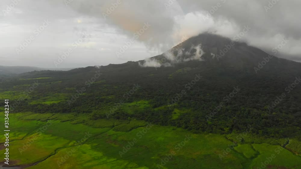 Aerial shot of Arenal volcano, Costa Rica. Shot from El Castillo village with green landscape in front, cloudy weather. Aerial shot of Arenal volcano, Costa Rica. Shot from El Castillo village with green landscape in front, cloudy weather.