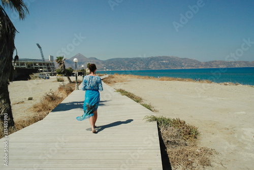 a girl walks along a wooden path along the sea, Heraklion