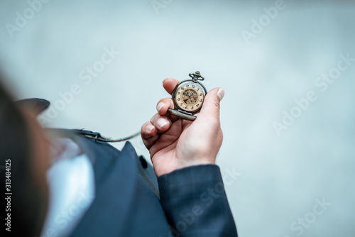 Man is holding and checking his classic pocket watch. Vintage, classic concept . 