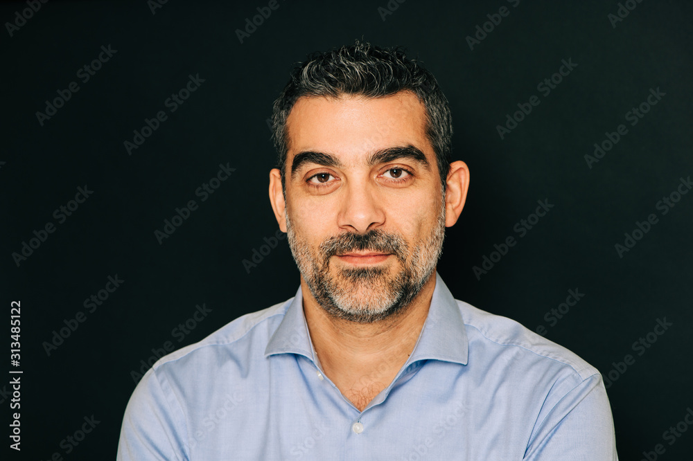 Studio portrait of handsome man wearing formal blue shirt, posing on black background Studio portrait of handsome man wearing formal blue shirt, posing on black background