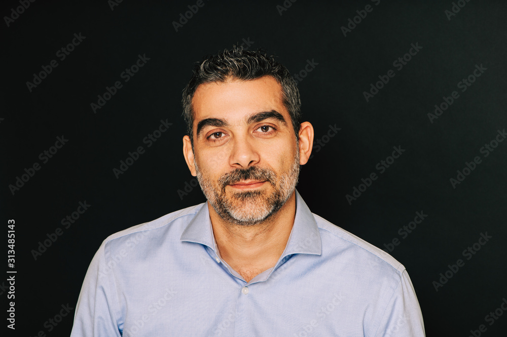 Obraz premium Studio portrait of handsome man wearing formal blue shirt, posing on black background