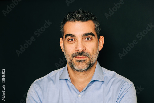 Studio portrait of handsome man wearing formal blue shirt, posing on black background