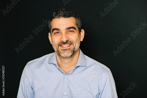 Studio portrait of handsome man wearing formal blue shirt, posing on black background © annanahabed