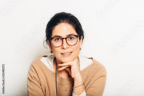 Fotografie Studio portrait of beautiful brunette woman, wearing glasses, leaning on a hand,
