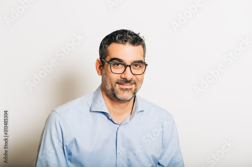 Studio portrait of handsome man wearing formal blue shirt and glasses, posing on white background © annanahabed
