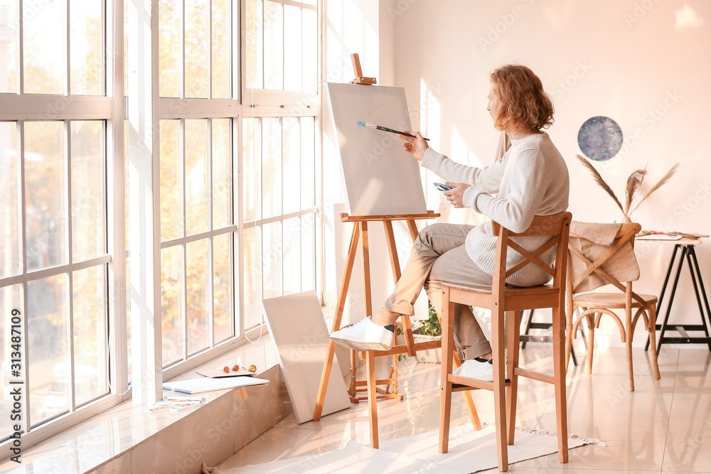 Young male artist painting in studio Young male artist painting in studio