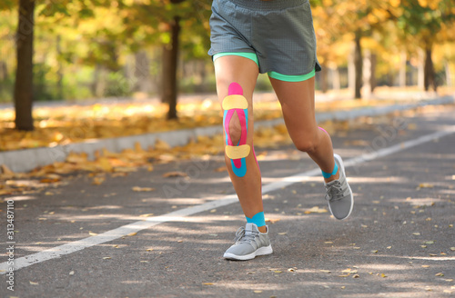 Sporty woman with physio tape running in park