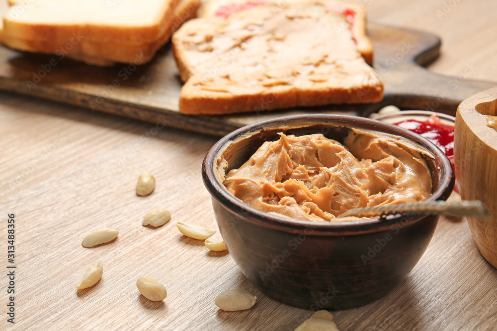 Tasty peanut butter in bowl on wooden table Tasty peanut butter in bowl on wooden table