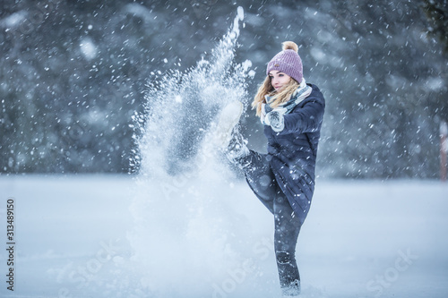Young woman in warm clothes is having fun out of the snow