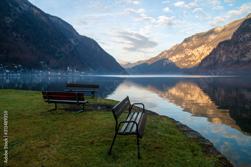 Peaceful landscape with park benches in front of calm lake and view of Hallstatt mountains village in Austria afternoon before sunset © Radoslav Cajkovic