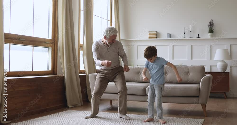 Happy two age generations active family dancing in living room