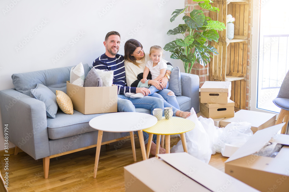 Beautiful family with kid sitting on the sofa drinking coffee at new home around cardboard boxes Beautiful family with kid sitting on the sofa drinking coffee at new home around cardboard boxes