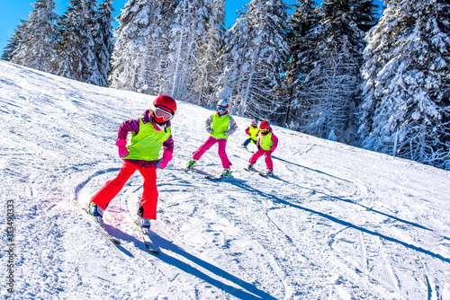 Group of kids learning how to ski on slope in mountains during winter vacation