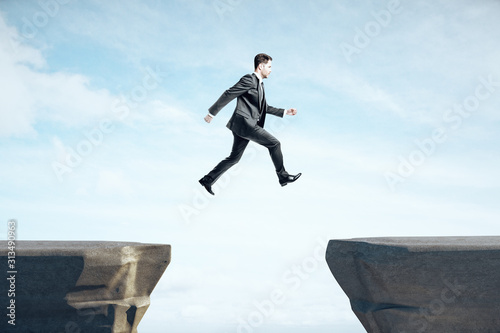 Businessman in suit jumping on mountain