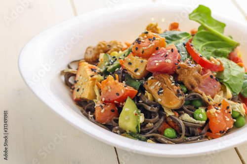 Tasty soba pasta with seafood and vegetables on wooden table