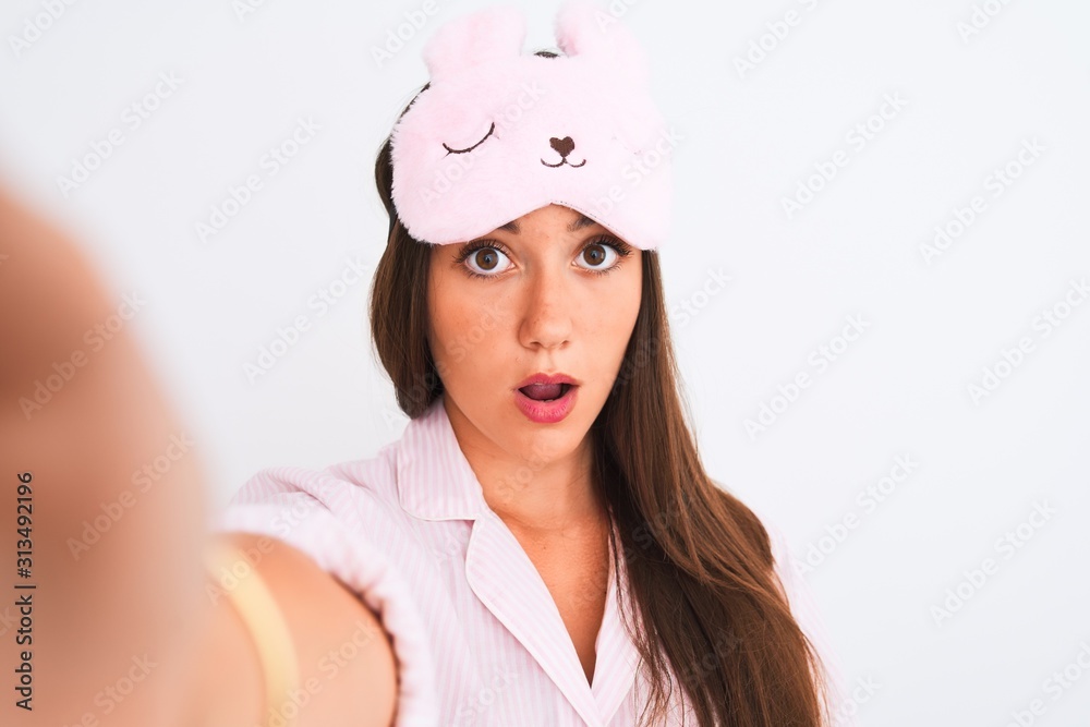 Girl wearing pajama and sleep mask make selfie by camera over isolated white background scared in shock with a surprise face, afraid and excited with fear expression Girl wearing pajama and sleep mask make selfie by camera over isolated white background scared in shock with a surprise face, afraid and excited with fear expression