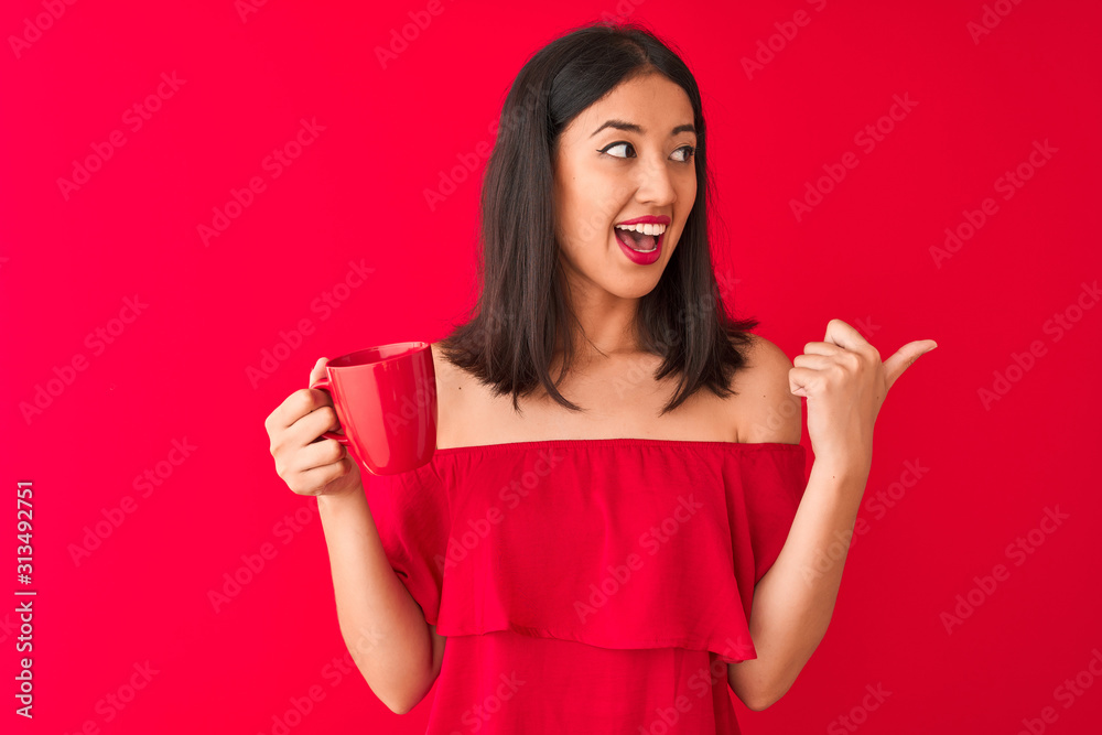 Young beautiful chinese woman drinking cup of coffee standing over isolated red background pointing and showing with thumb up to the side with happy face smiling Young beautiful chinese woman drinking cup of coffee standing over isolated red background pointing and showing with thumb up to the side with happy face smiling