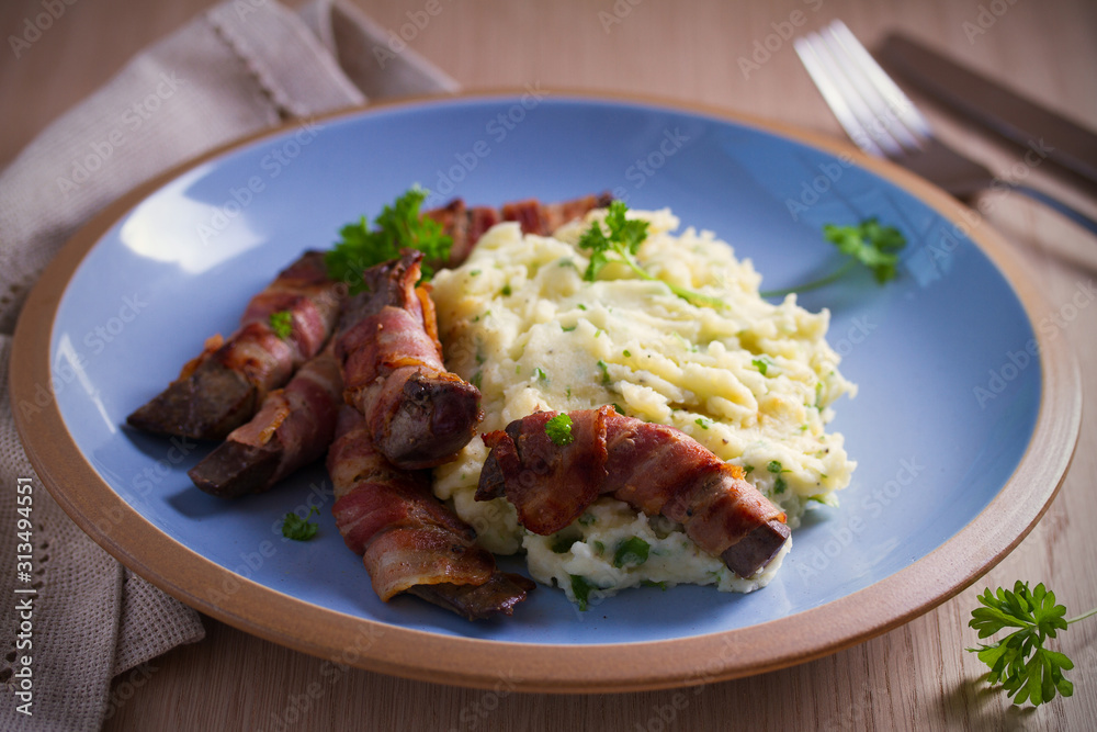 Beef liver wrapped in bacon with mash potato on blue table. horizontal image Beef liver wrapped in bacon with mash potato on blue table. horizontal image
