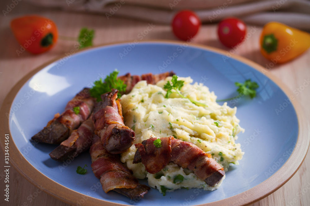 Beef liver wrapped in bacon with mash potato on blue table. horizontal image Beef liver wrapped in bacon with mash potato on blue table. horizontal image