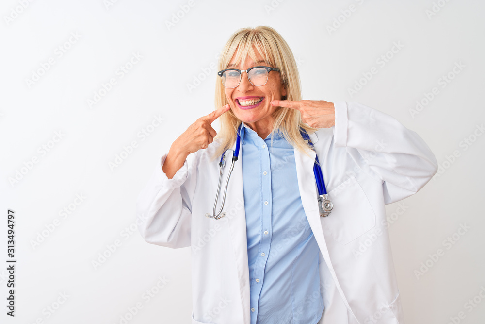 Middle age doctor woman wearing glasses and stethoscope over isolated white background smiling cheerful showing and pointing with fingers teeth and mouth. Dental health concept. Middle age doctor woman wearing glasses and stethoscope over isolated white background smiling cheerful showing and pointing with fingers teeth and mouth. Dental health concept.