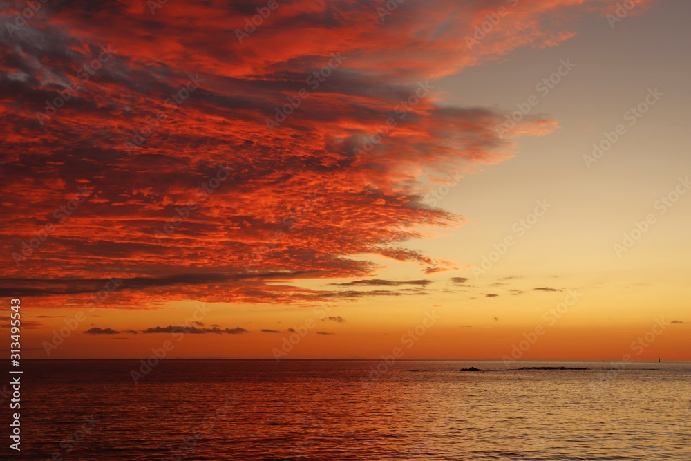 Sunset over the southern calm sea and scarlet thick clouds