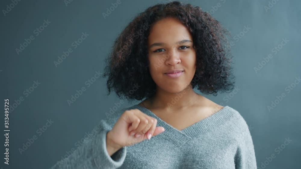 Portrait of beautiful African American girl showing thumbs-down gesture on dark background smiling looking at camera. Emotions and lifestyle concept. Portrait of beautiful African American girl showing thumbs-down gesture on dark background smiling looking at camera. Emotions and lifestyle concept.