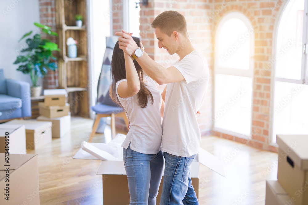 Young beautiful couple dancing at new home around cardboard boxes Young beautiful couple dancing at new home around cardboard boxes