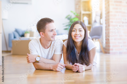 Young beautiful couple lying down at new home around cardboard boxes