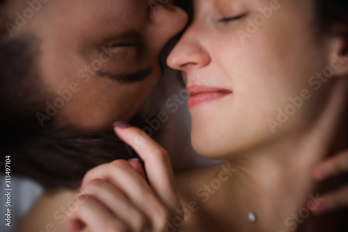 Defocused Top view of couple in love. Close-up portrait of the Lovers on the bed at home, head to head. The morning of the newlyweds, tenderly resting on festive day off at home. Concept of tactility