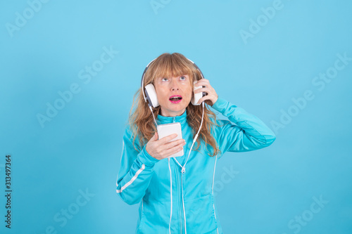 adult woman wearing sportswear with headphones and mobile phone isolated on color background