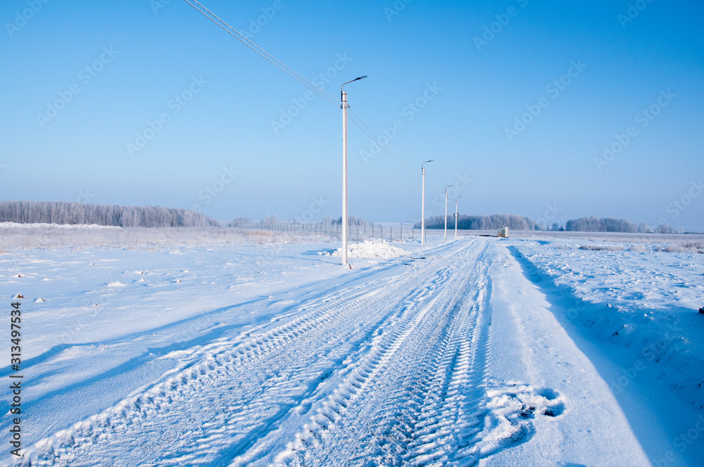 Electric pole of power lines and wires with blue sky on a background of a winter landscape