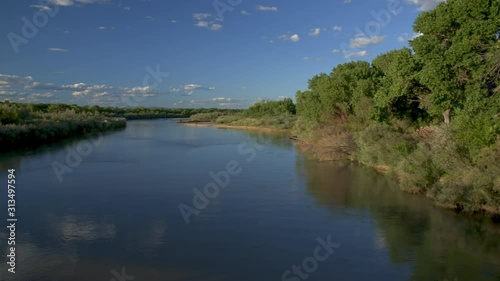 Super wide, beautiful right to left pan of Rio Grande river with cobalt blue water and skies against emerald green river flora. photo